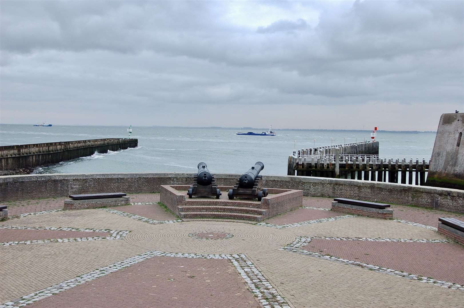 Old cannons still guard the harbour entrance as ships pass going to Antwerp.