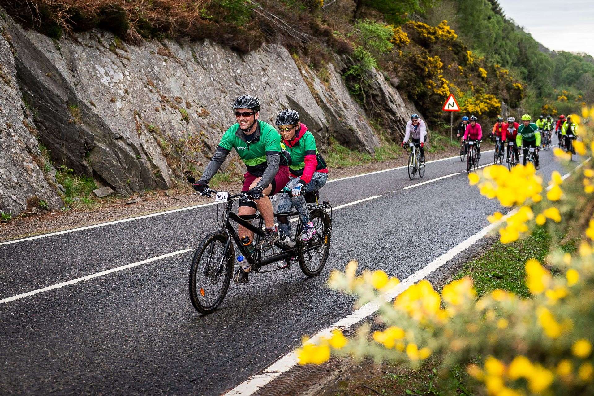A pair of Macmillan Cancer Support cyclists riding a tandom bike as part of the Etape Loch Ness.
