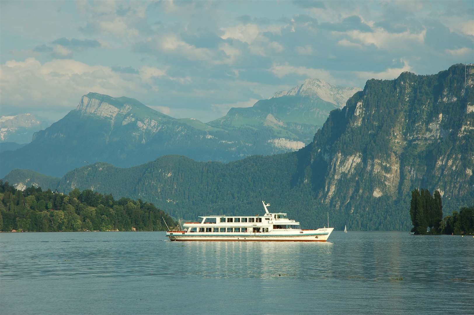 The majestic scenery and clear blue waters of the lake reflect on the MV Brunnen as it comes back to Luzern from a trip down the lake.