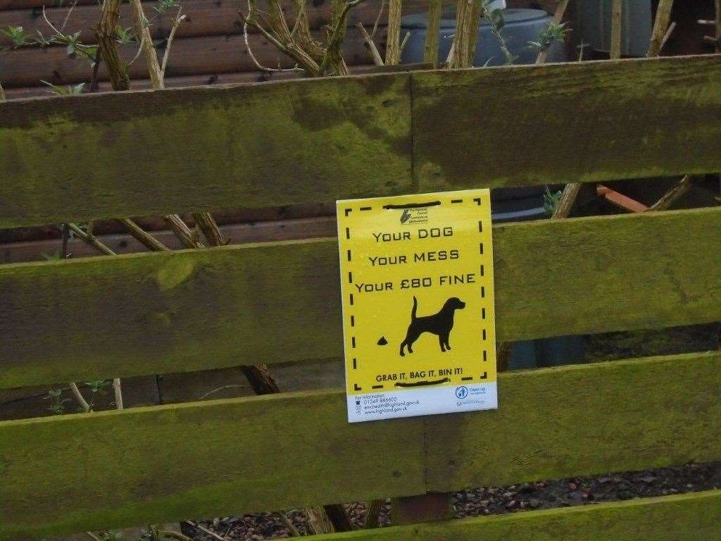 A council sign warns that dog owners may face fines if they don't clean up after their pets.