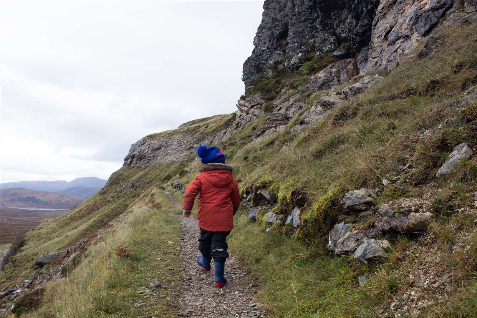 Matthew strides ahead beside the ancient rocks of Knockan Crag.