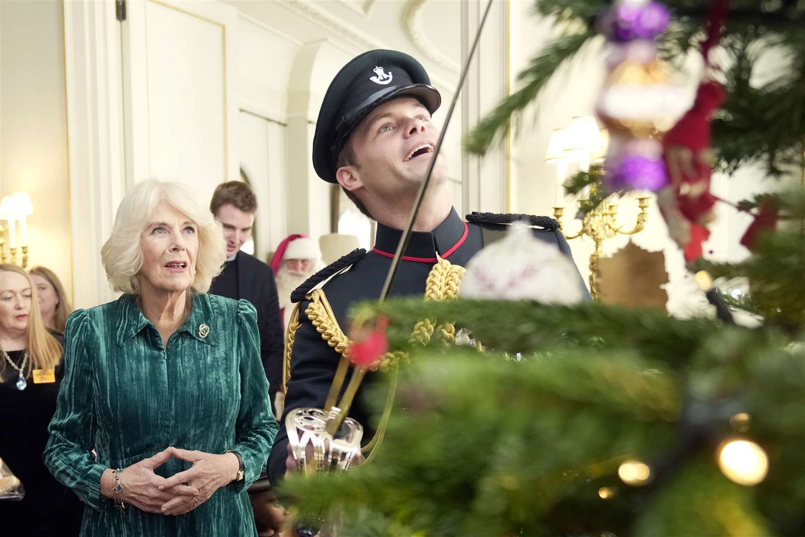 The Queen watches as a former equerry places a decoration on the Christmas tree with his sable (Kin Cheung/PA)