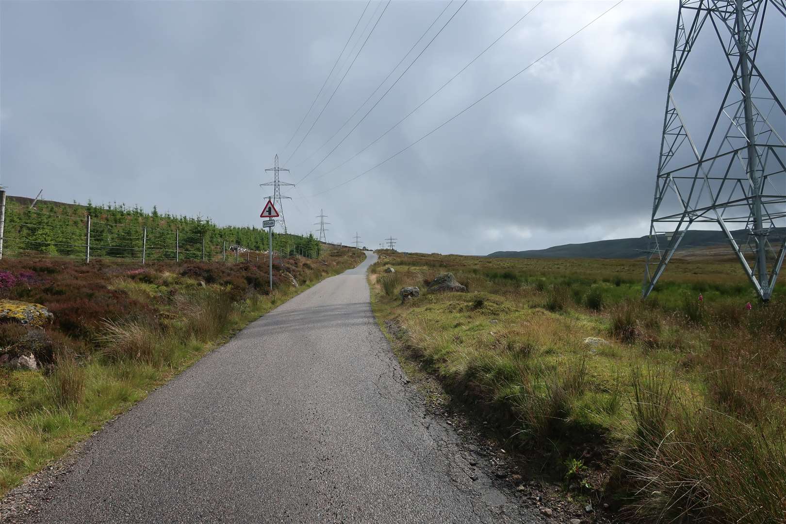 The road climbs between the pylons on its way to the wind farm.