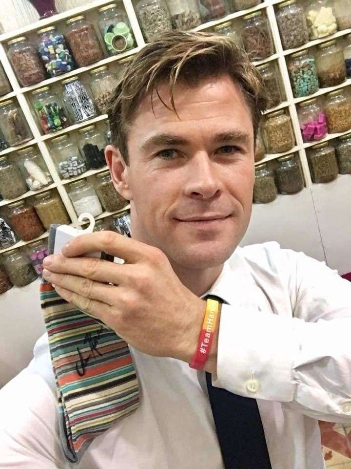 Avengers star Chris Hemswood holding the signed Team Hamish socks and wearing its wristbands.