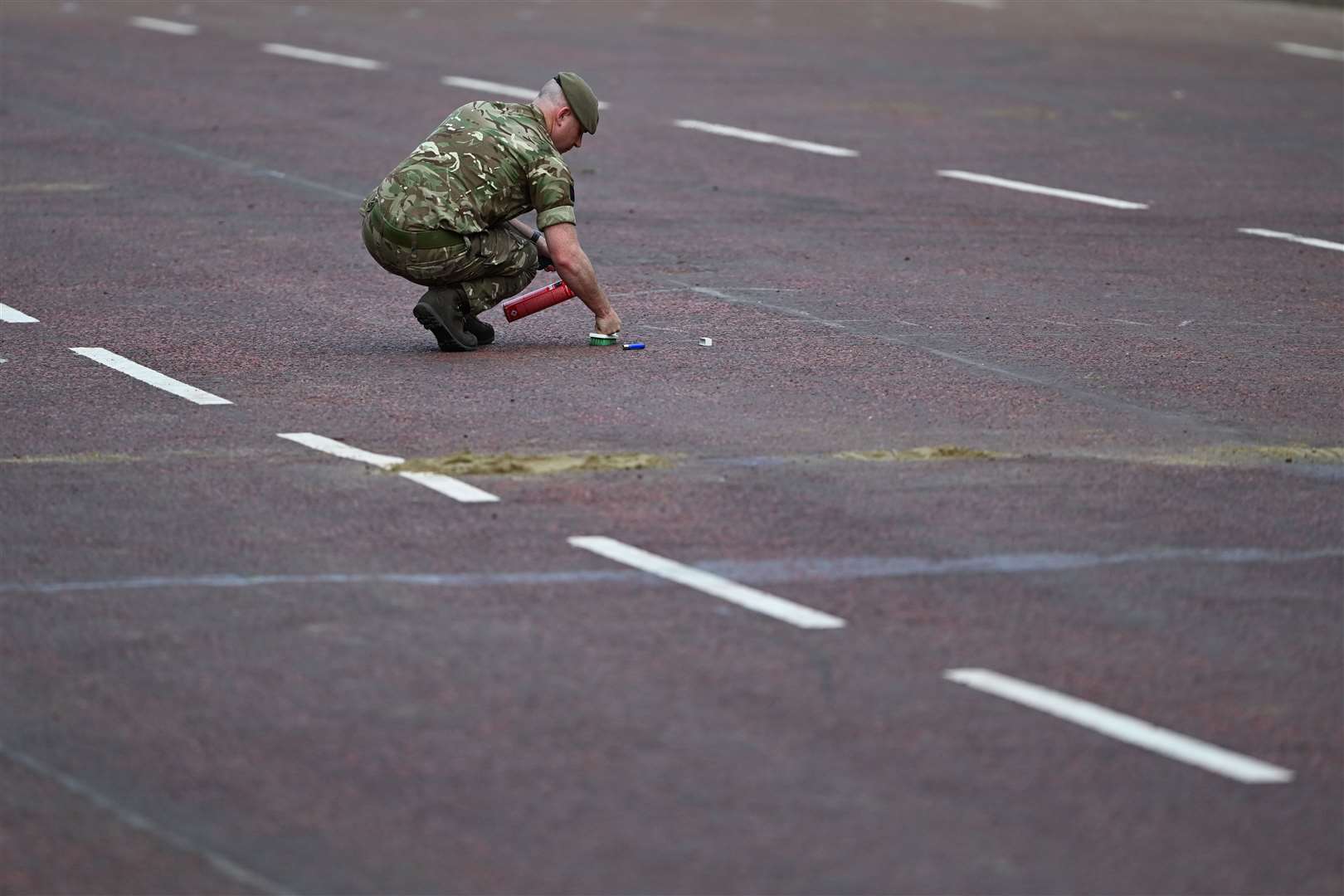 An Army officer is seen cleaning the road (Charles McQuillan/PA)