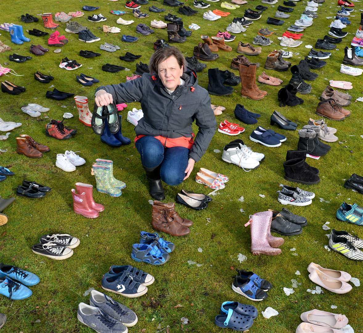 Highland Action Group's Barbara Irvine with 230 pairs of shoes, representing the number of children who will not be at school if cuts go ahead.