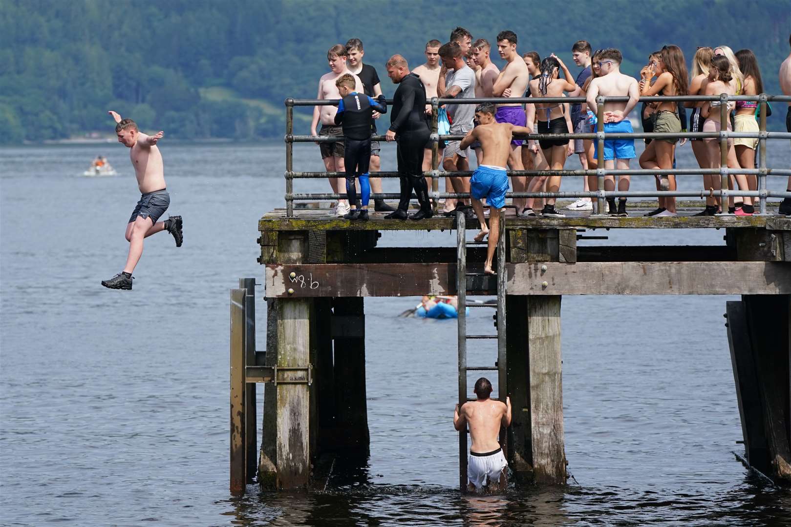 People diving off the pier at Loch Lomond, in the village of Luss in Argyll (Andrew Milligan/PA)