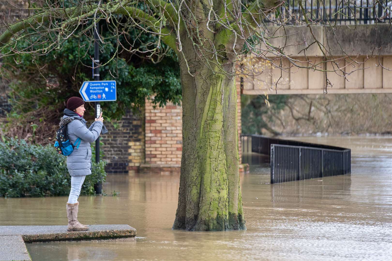 A woman takes a photo of flooding in Bedford (Joe Giddens/PA) 