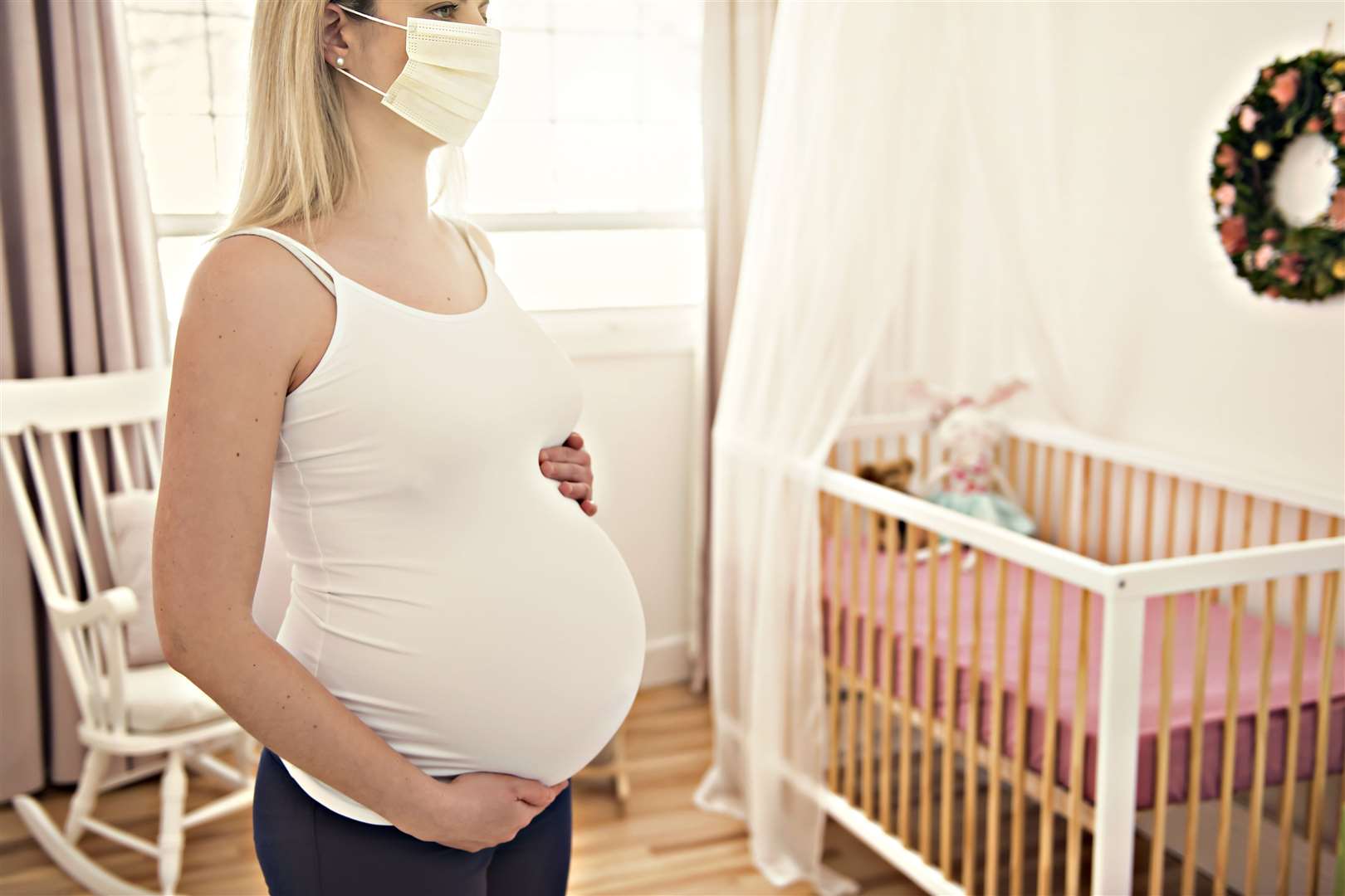 A pregnant woman use surgical mask close her mouth and nose at home