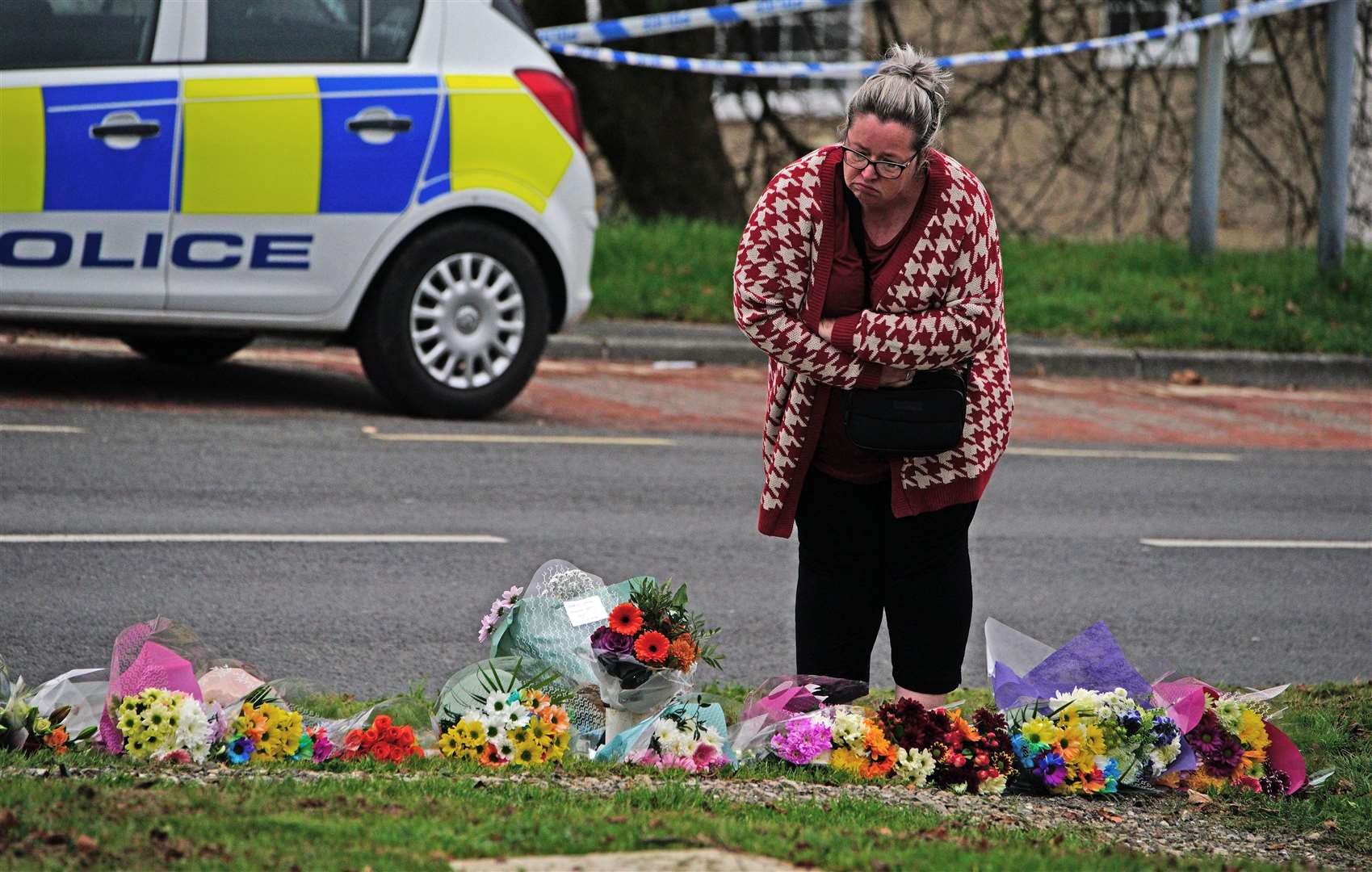 A woman lays flowers on Sheepstor Road in Plymouth after a woman’s body was found (Ben Birchall/PA)