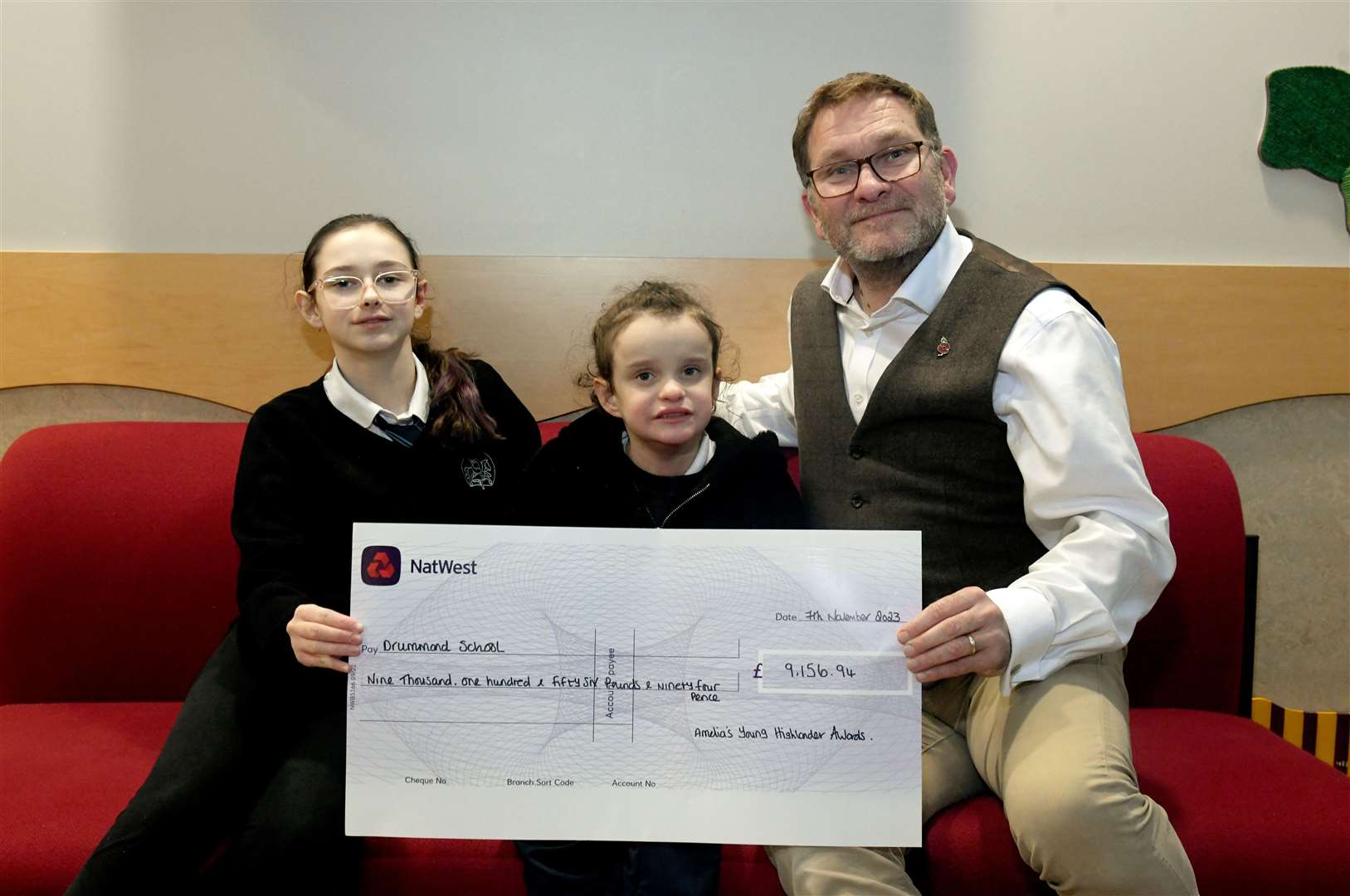 Savannah Kelly with her sister, Amelia-Jo, present a cheque for £9156 to Mark Elvines, headmaster of Drummond School. Picture: James Mackenzie.