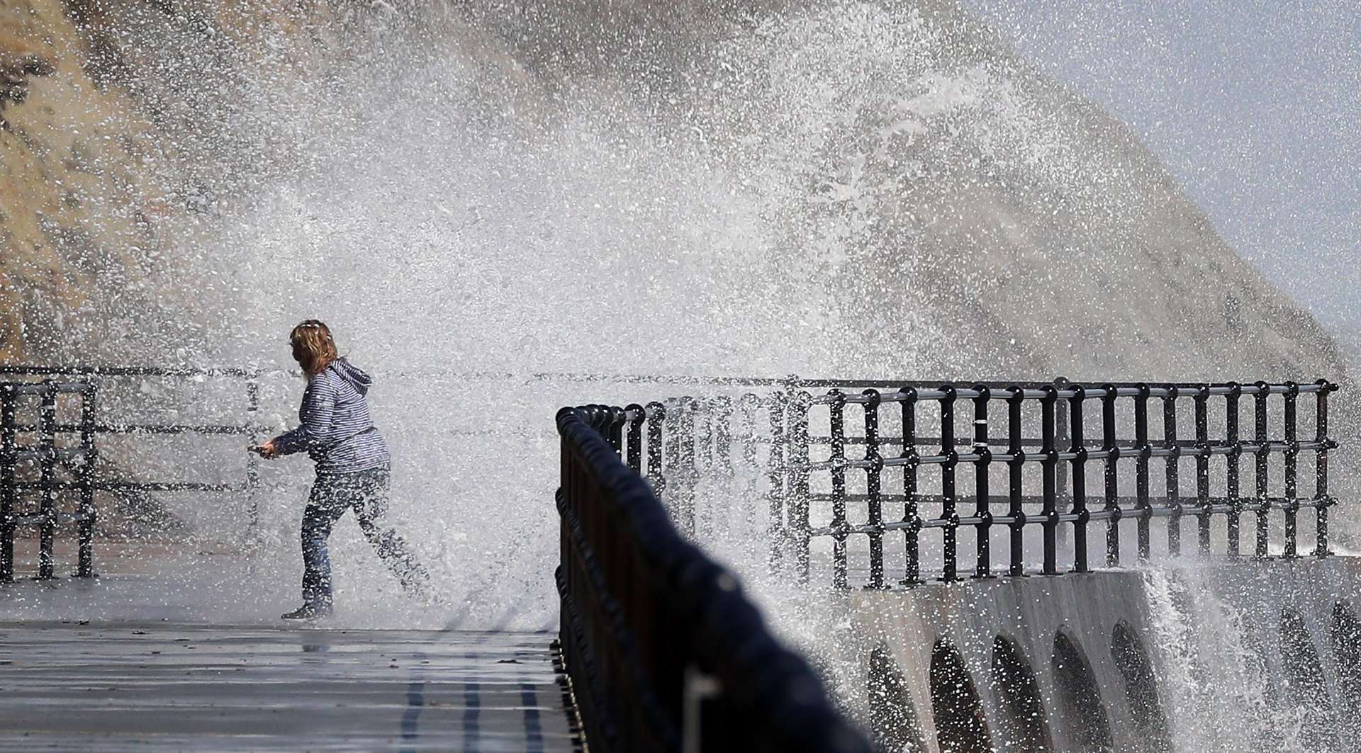 A lady is caught by a wave crashing over the promenade in Folkestone, Kent (Gareth Fuller/PA)