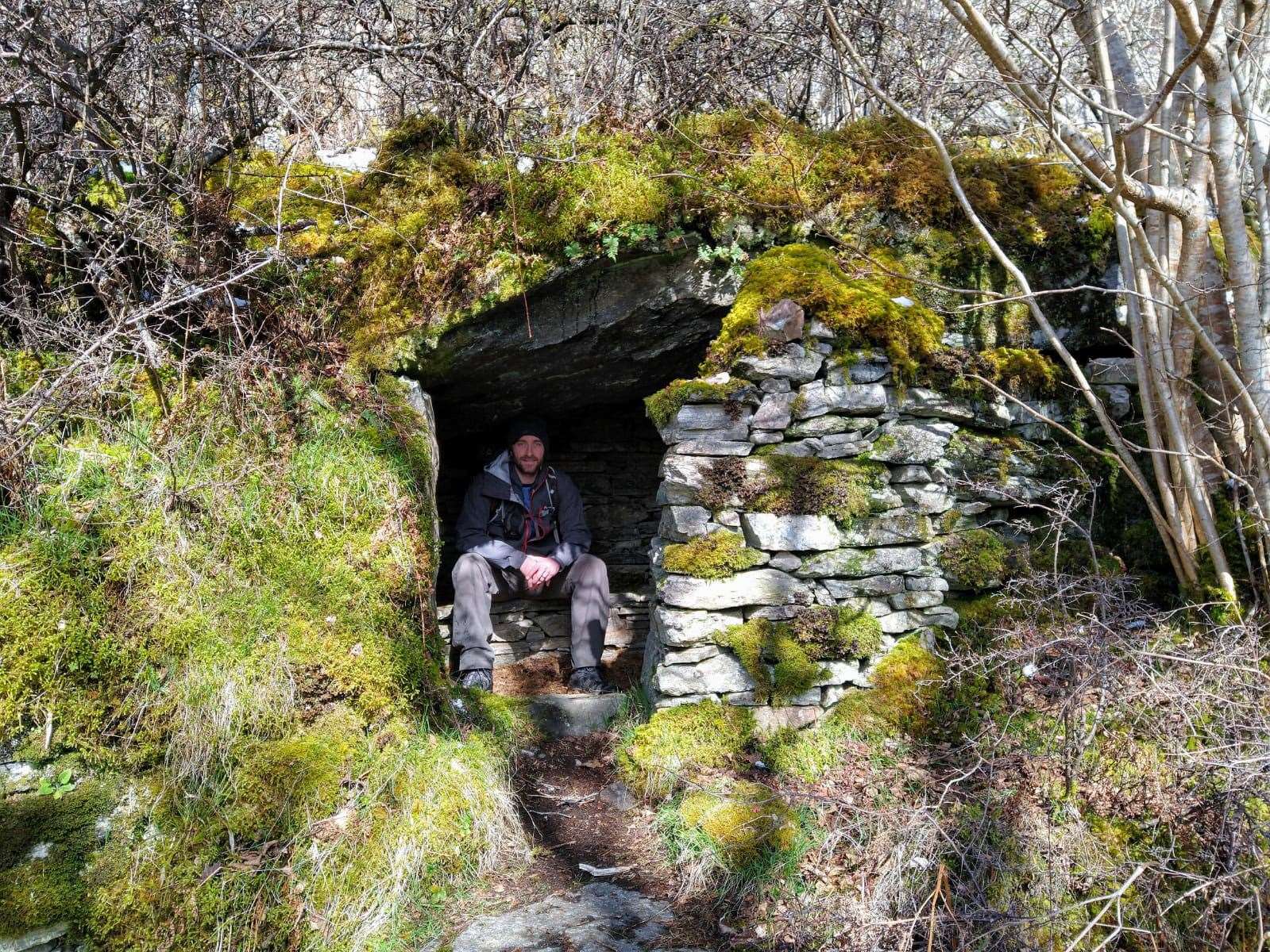 John takes a seat in the stone cave.