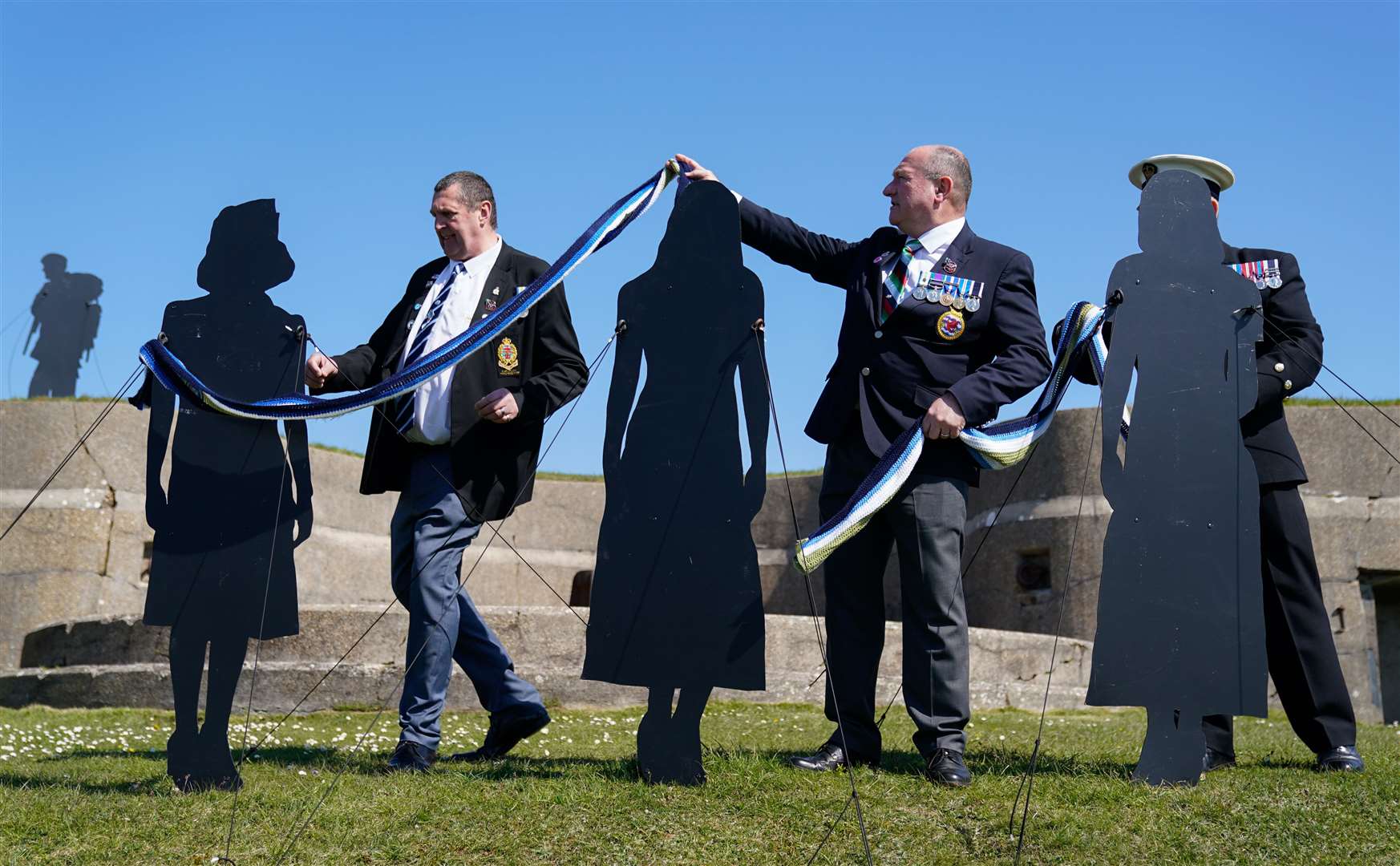 Falklands veterans Barrie Jones (left) and Andy Gatherer place a scarf over three silhouettes (Andrew Matthews/PA)
