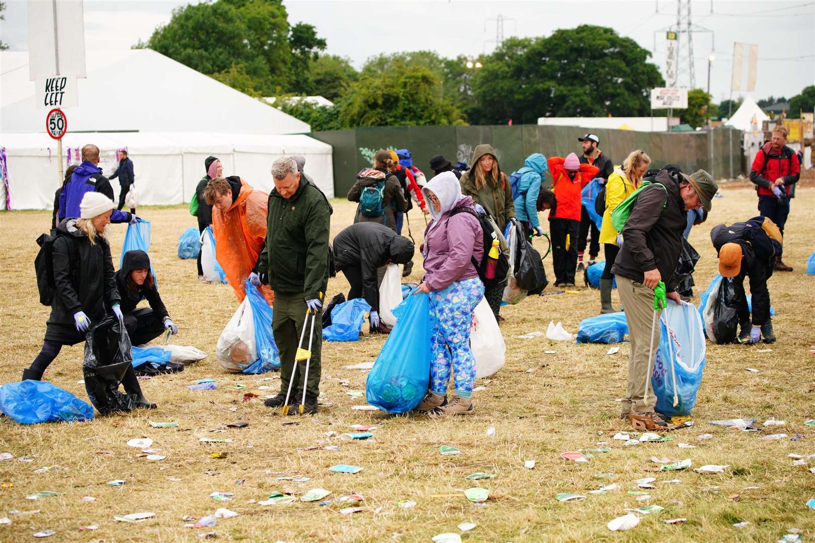 Litter-pickers work to clear the mess left by thousands of revellers (Ben Birchall/PA)