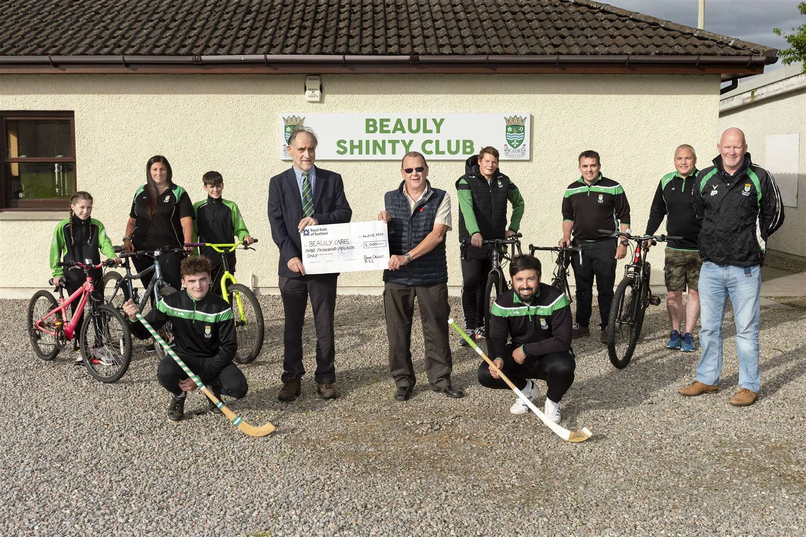 Beauly Shinty Club President David Calder (centre left) presents the £3000 cheque to George Borland of Beauly Cares.