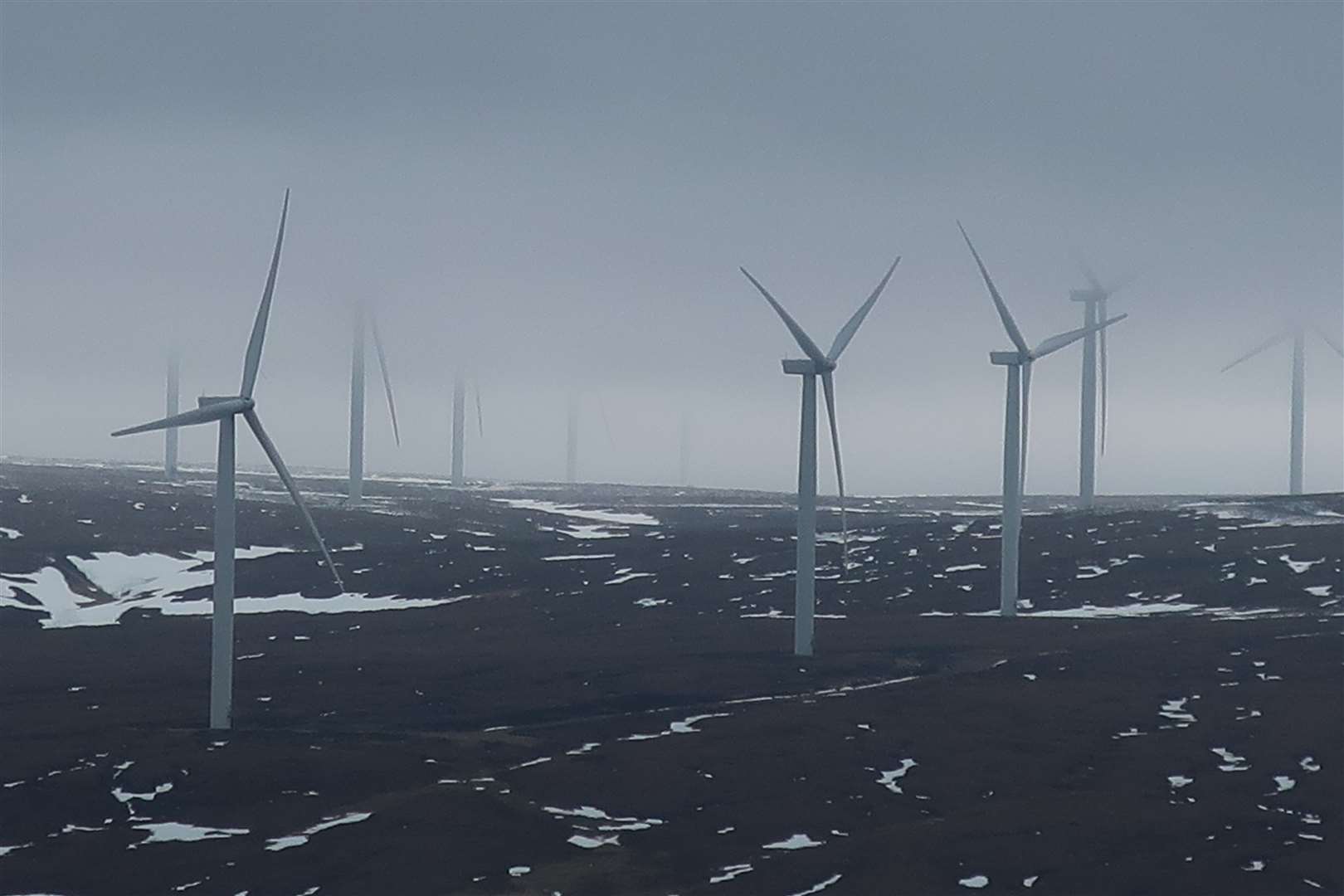 The nearby turbines of Dunmaglass wind farm under a low blanket of cloud.