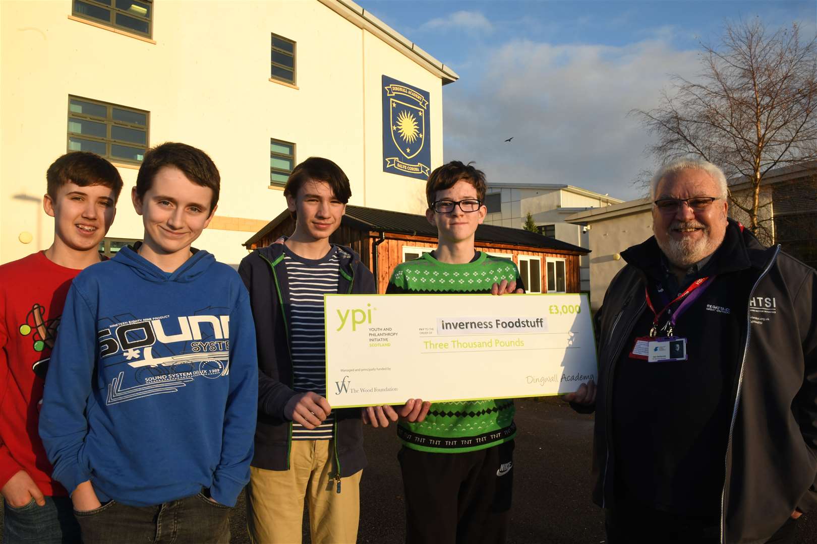 Dingwall Academy S3 pupils Harry Stewart, Seth Hitchen, Magnus Atkinson and Angus Porter hand over the donation to Iain McKenzie, vice chairman of Inverness Foodstuff. Picture: James Mackenzie.