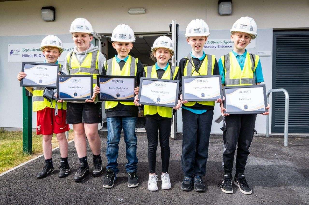 Pupils of the construction forum proudly present their certificates of achievement outside the building's entrance. Photo by Tim Winterburn