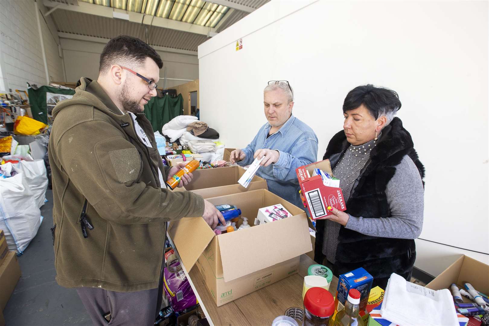 Kinga Orkisz with her husband Paul and son Konrad, who moved to Northern Ireland 16 years ago from Poland, sort supplies at their south Belfast business unit on Apollo Road to be sent to help the Ukrainian people (Liam McBurney/PA)