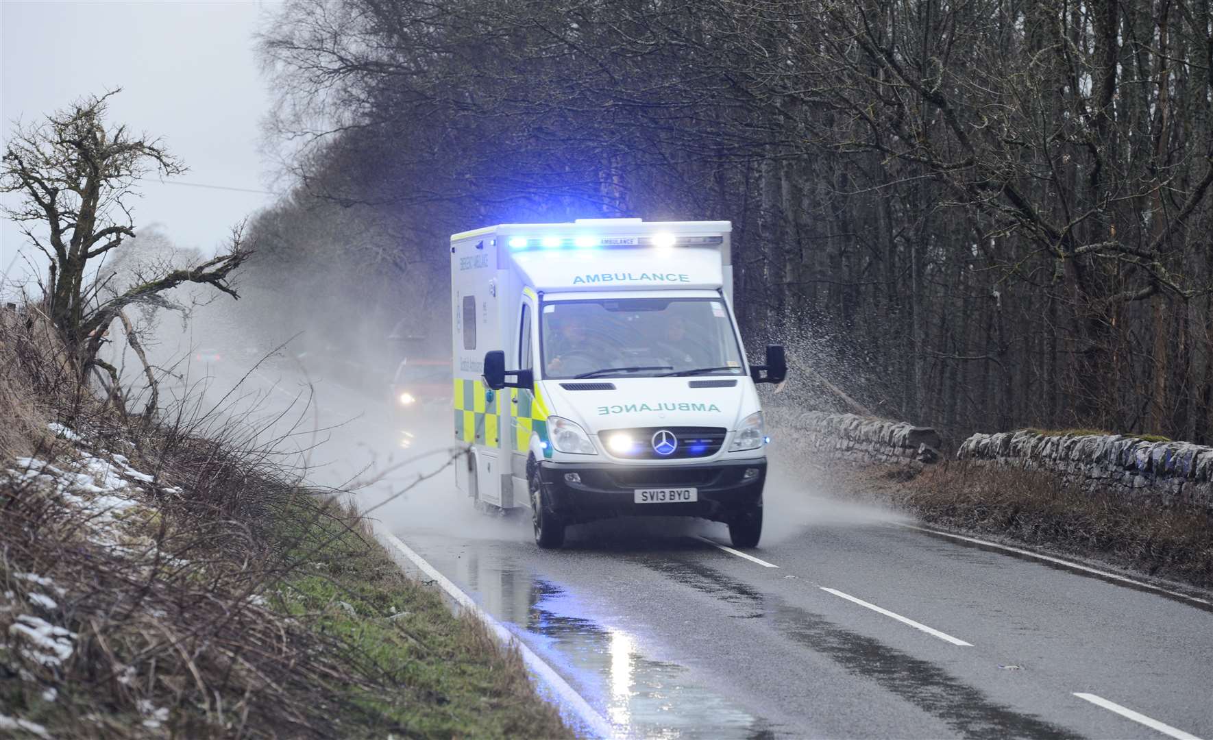 An ambulance overtakes a car in rain and snow-melt flooding. Picture: Alison White. Image No..