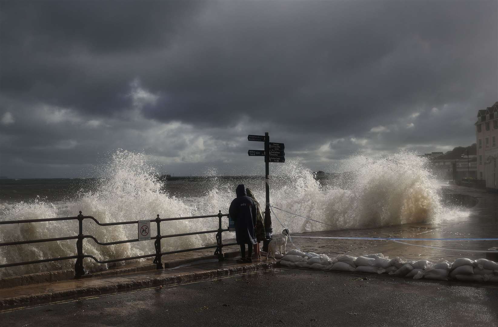 People watch as waves crash along the coast at Swanage in Dorset (Steve Parsons/PA)