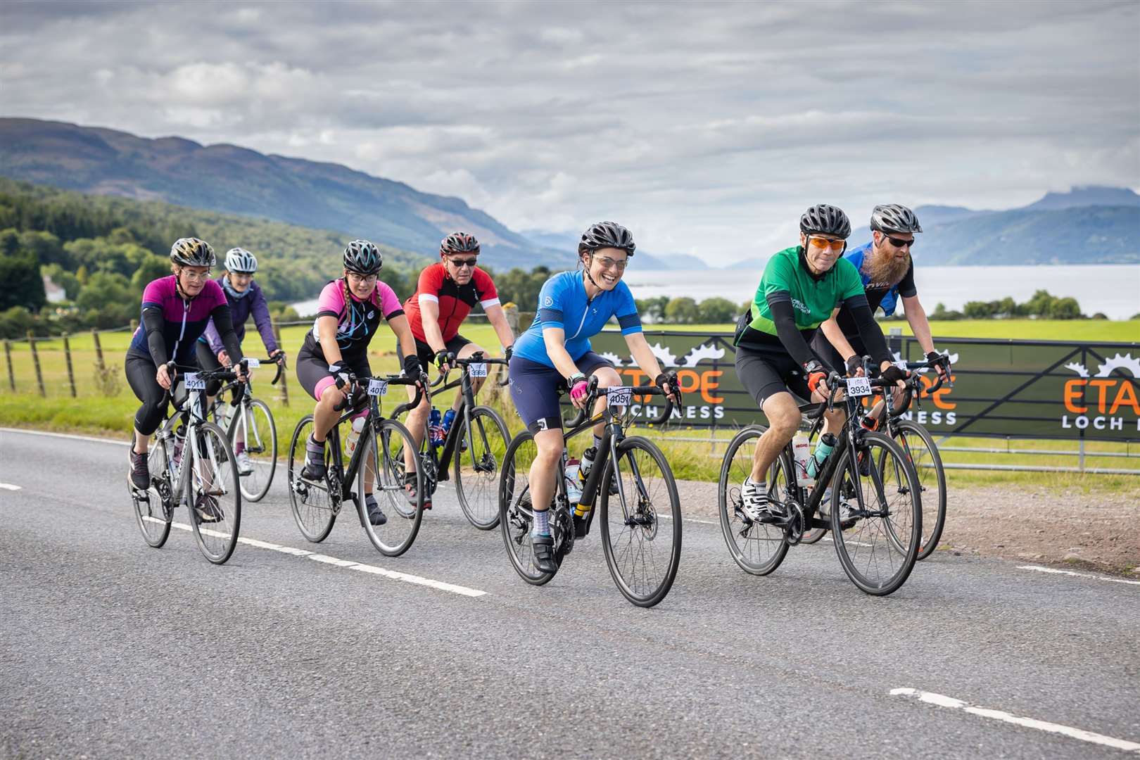 Riders in the Etape Loch Ness make their way up from Dores, with Loch Ness in the background.