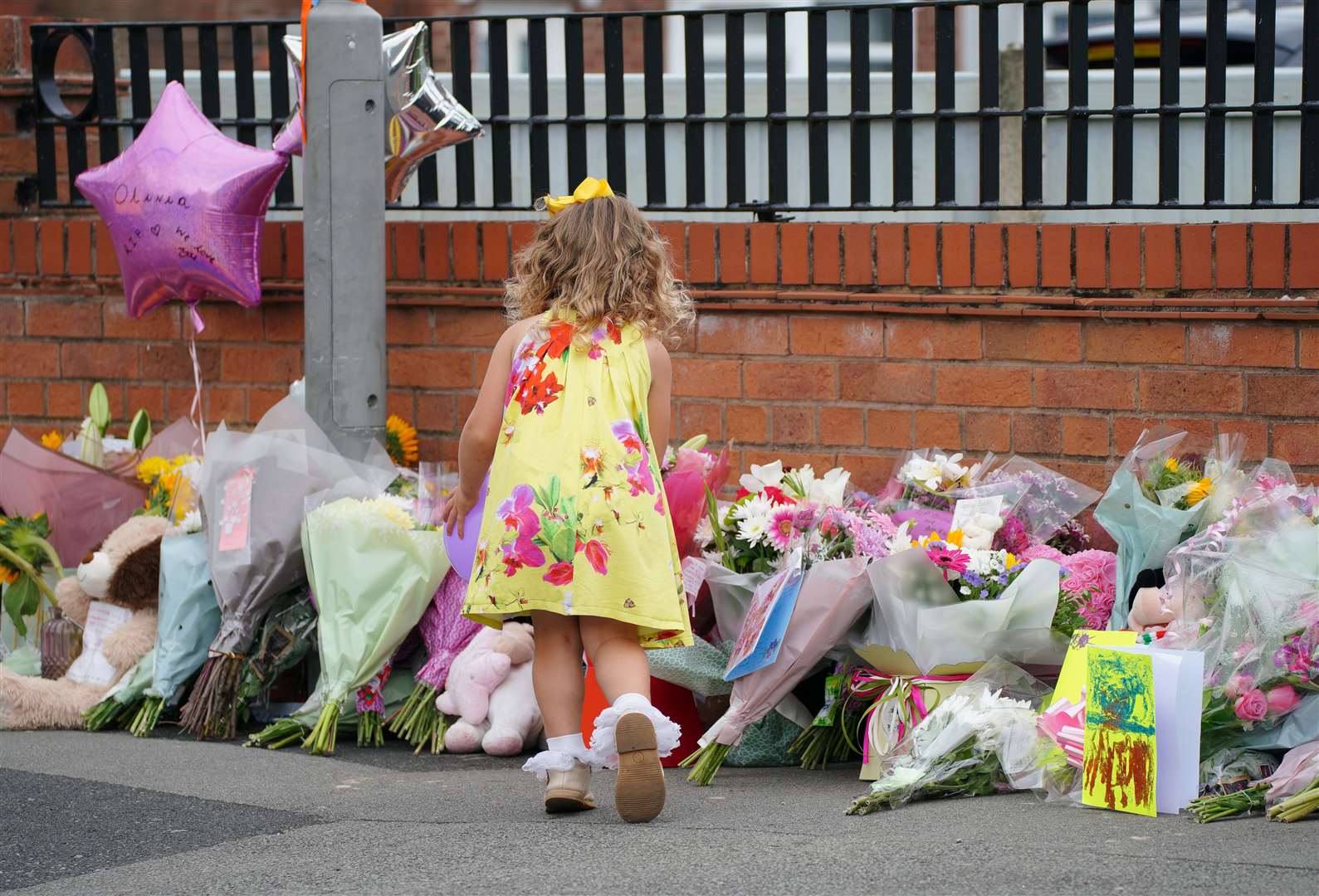 A young girl lays a tribute in Kingsheath Avenue, Liverpool, where nine-year-old Olivia Pratt-Korbel was fatally shot on Monday night (Peter Byrne/PA)