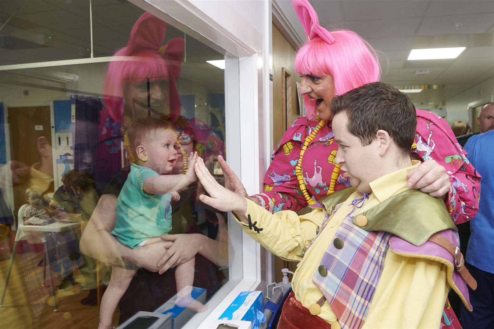 Through the window of infection control room, ten month old Aidan Mackay, Inverness, and mum Karina Murdoch are delighted to see Steve and Ross Allan.