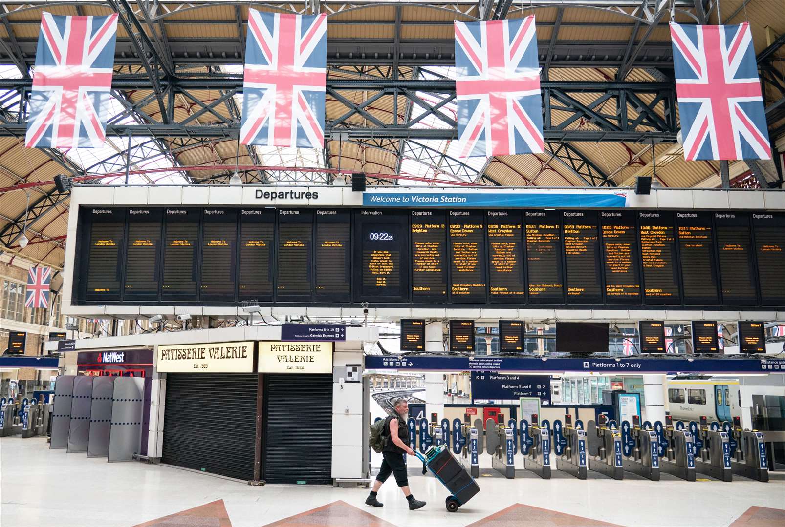A man passes departure boards at Victoria station in London (Dominic Lipinski/PA)