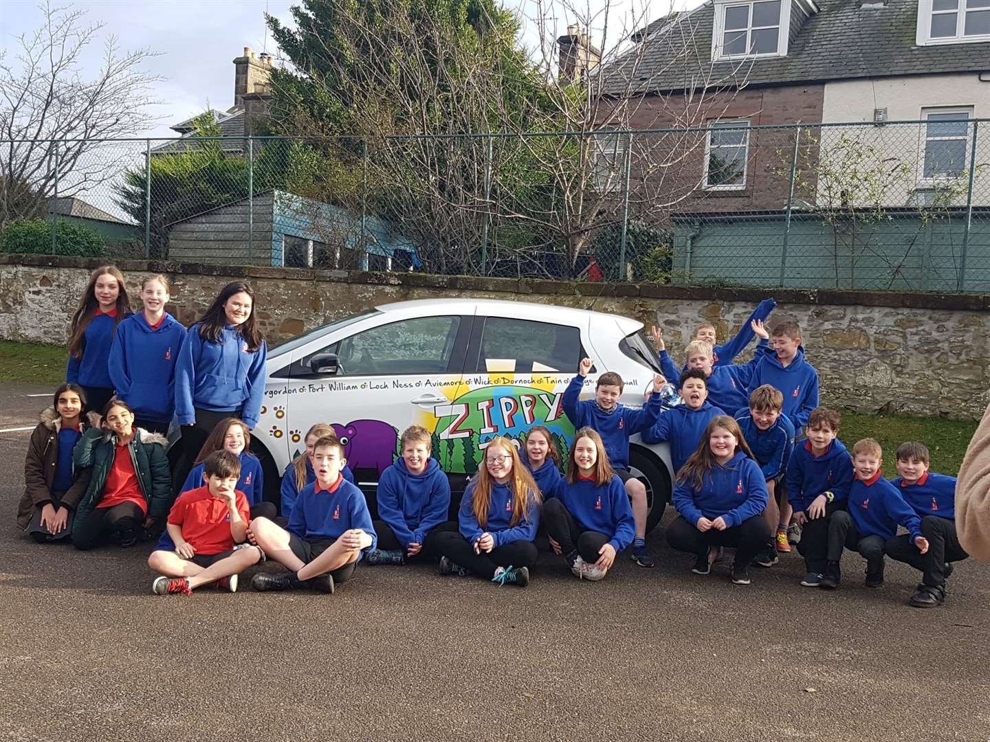 Crown Primary pupils with winner Aysha Reid (standing near the wing mirror) and Highland Council's electric vehicle (EV) Zippy Zoe.