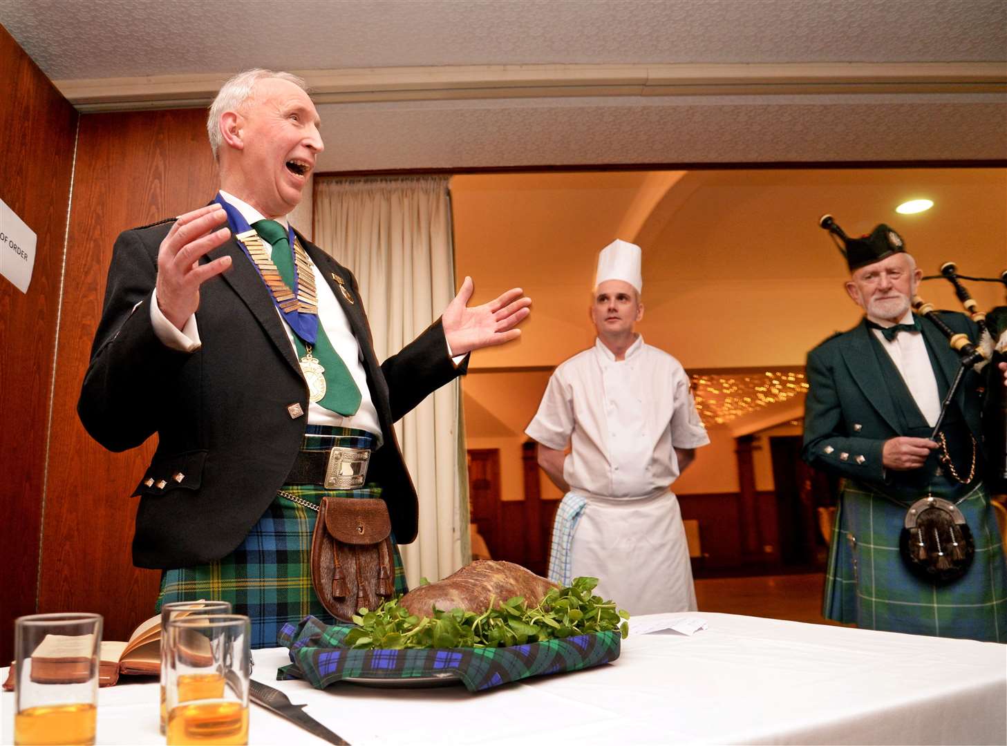 Iain Gordon, president of the Inverness Burns Club, recites the Address to a Haggis. Looking on are chef Alan Ludlow and piper Bill Hamilton.
