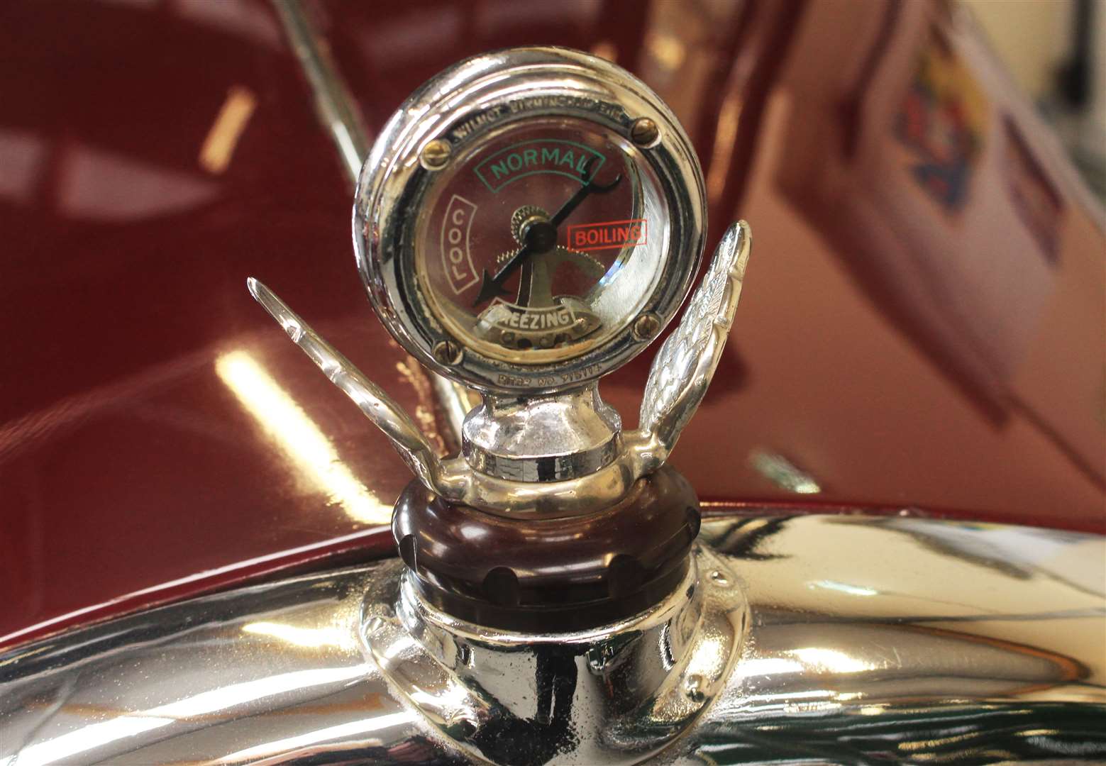 A radiator grille ornament with engine temperature gauge.