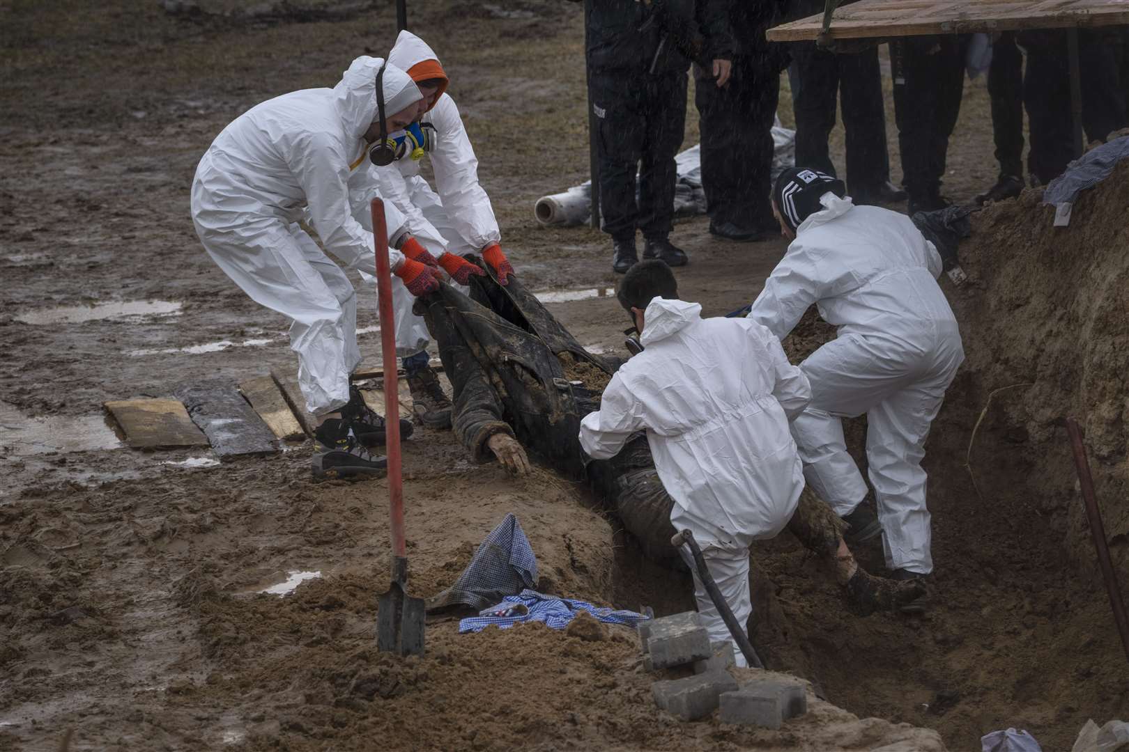 Cemetery workers remove a body from a mass grave in Bucha (Rodrigo Abd/AP)