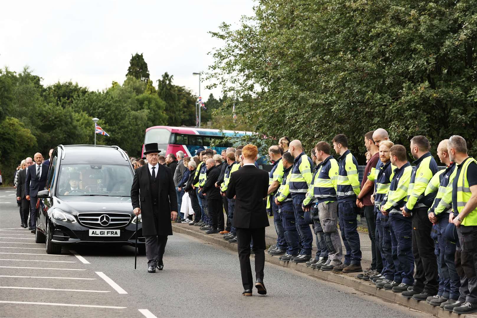 Employees stand outside the Wrightbus factory in Ballymena, as they watch the passing cortege (Liam McBurney/PA)