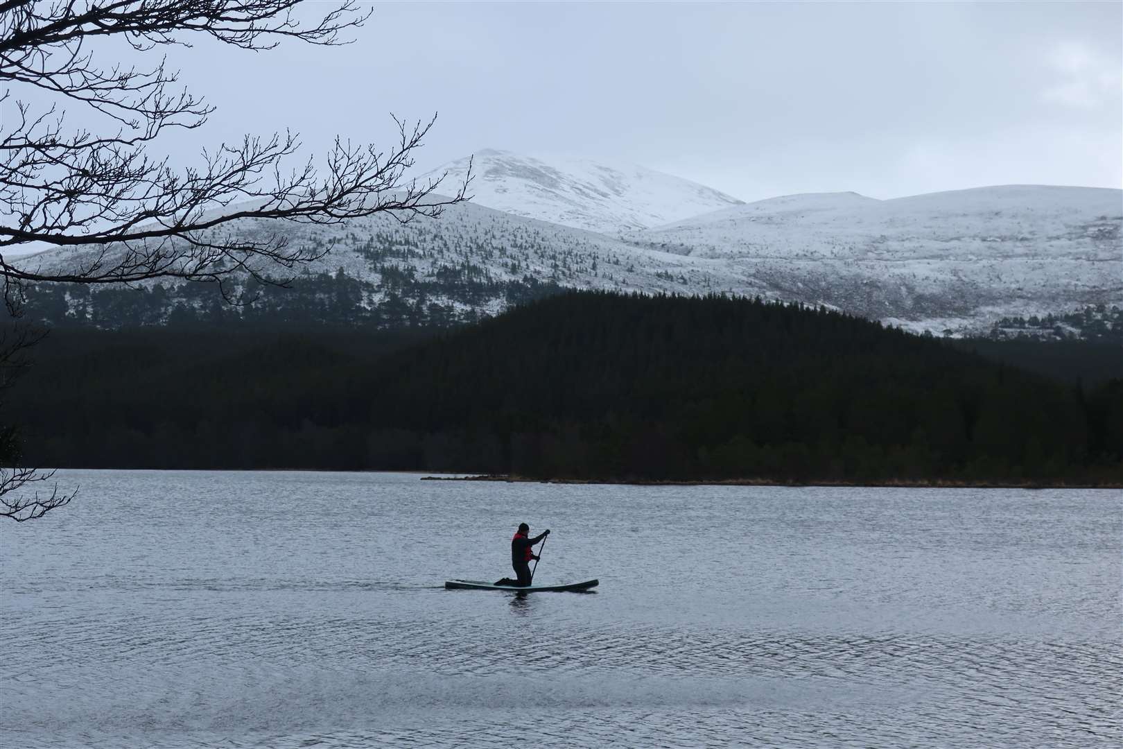 A paddleboarder glides across the loch.