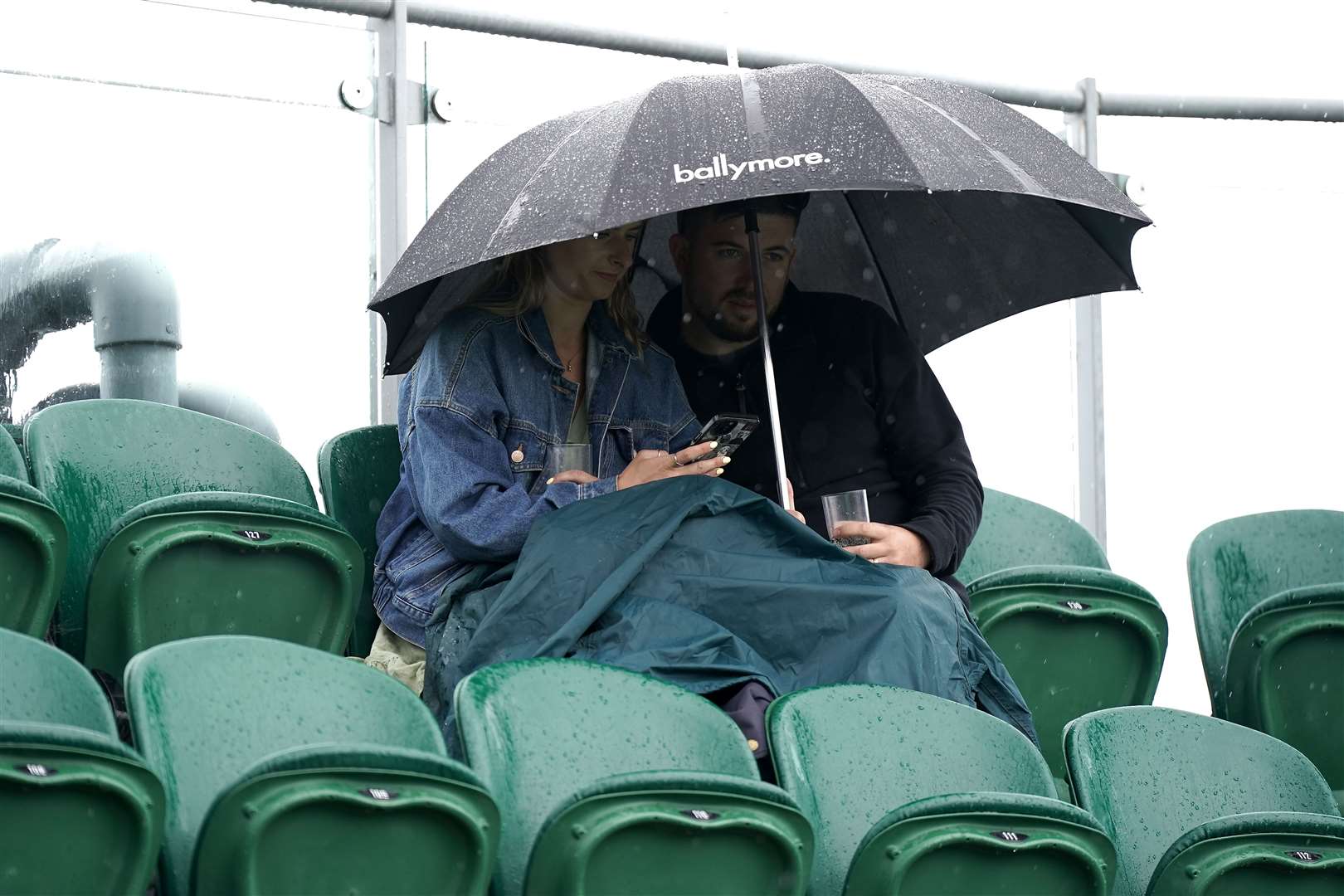 Spectators shield themselves from the rain during day one (Aaron Chown/PA)
