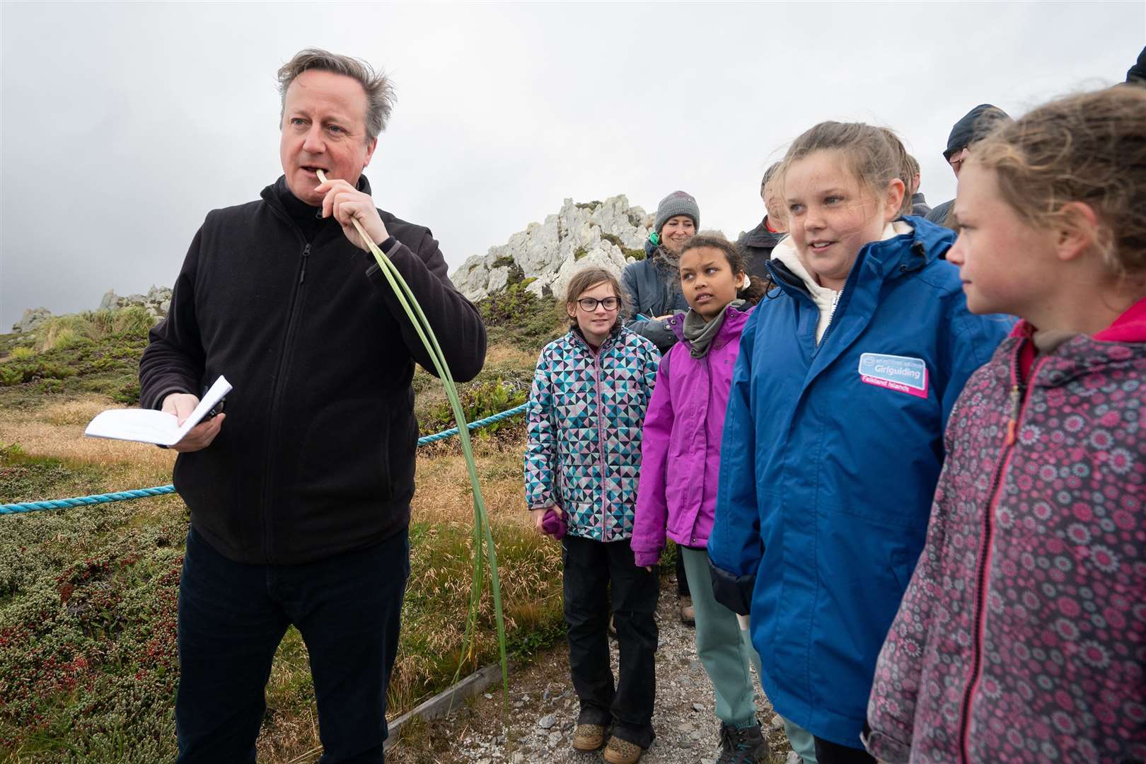 Lord Cameron tries eating some edible grass with local school children at Gypsy Cove (Stefan Rousseau/PA)