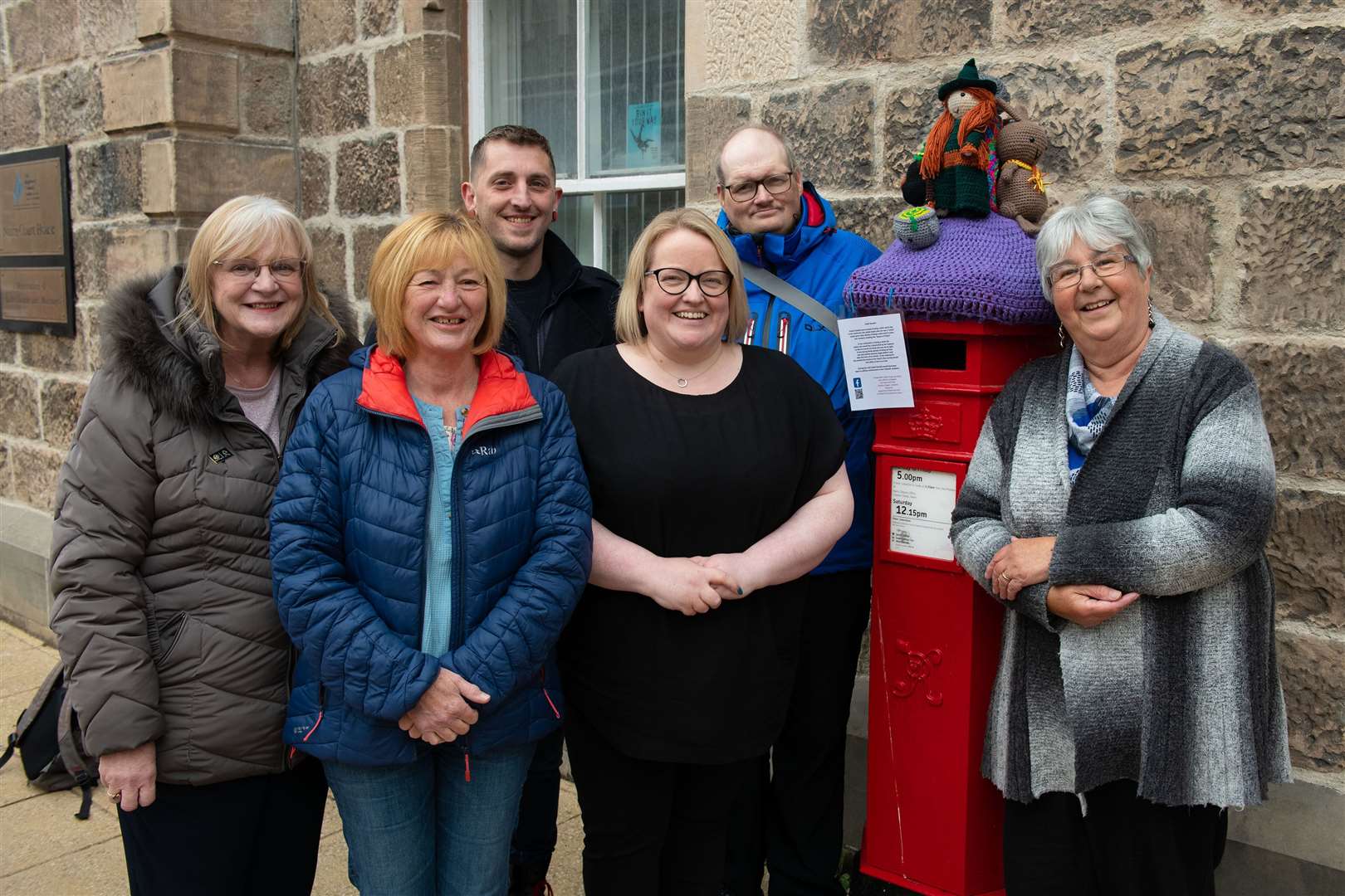 The Nairn Yarnbombers L/r Liz Le Brocq, Ann Forsyth, Adam Thompson, Kirsty Brown, Andrew Innes, Caroline Mackay, missing is member Morag Anderson,outside The Townhouse at The Isobel Gowdie display..