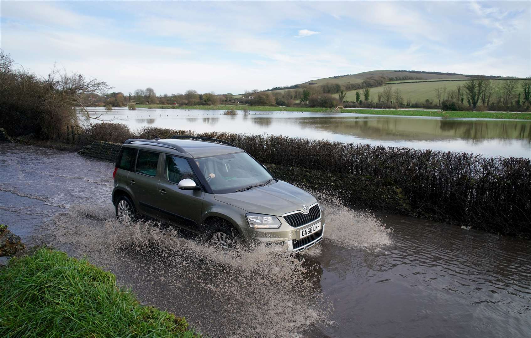 A car passes through floodwater from the Cuckmere River in Alfriston, East Sussex (Gareth Fuller/PA)