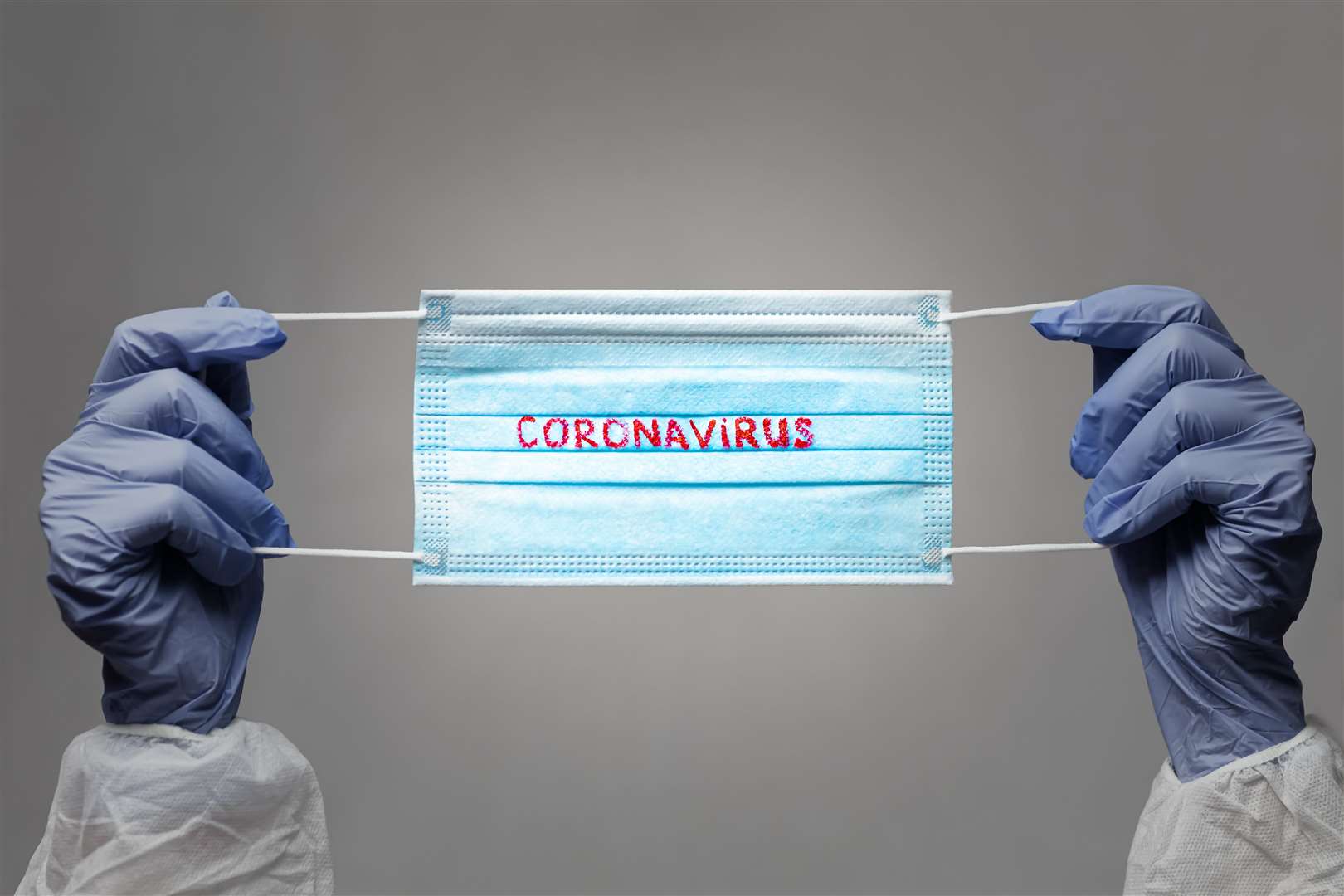 CORONAVIRUS. COVID-19 concept. blue medical face mask with a red inscription CORONAVIRUS in the hands of which are in rubber gloves. vignette image