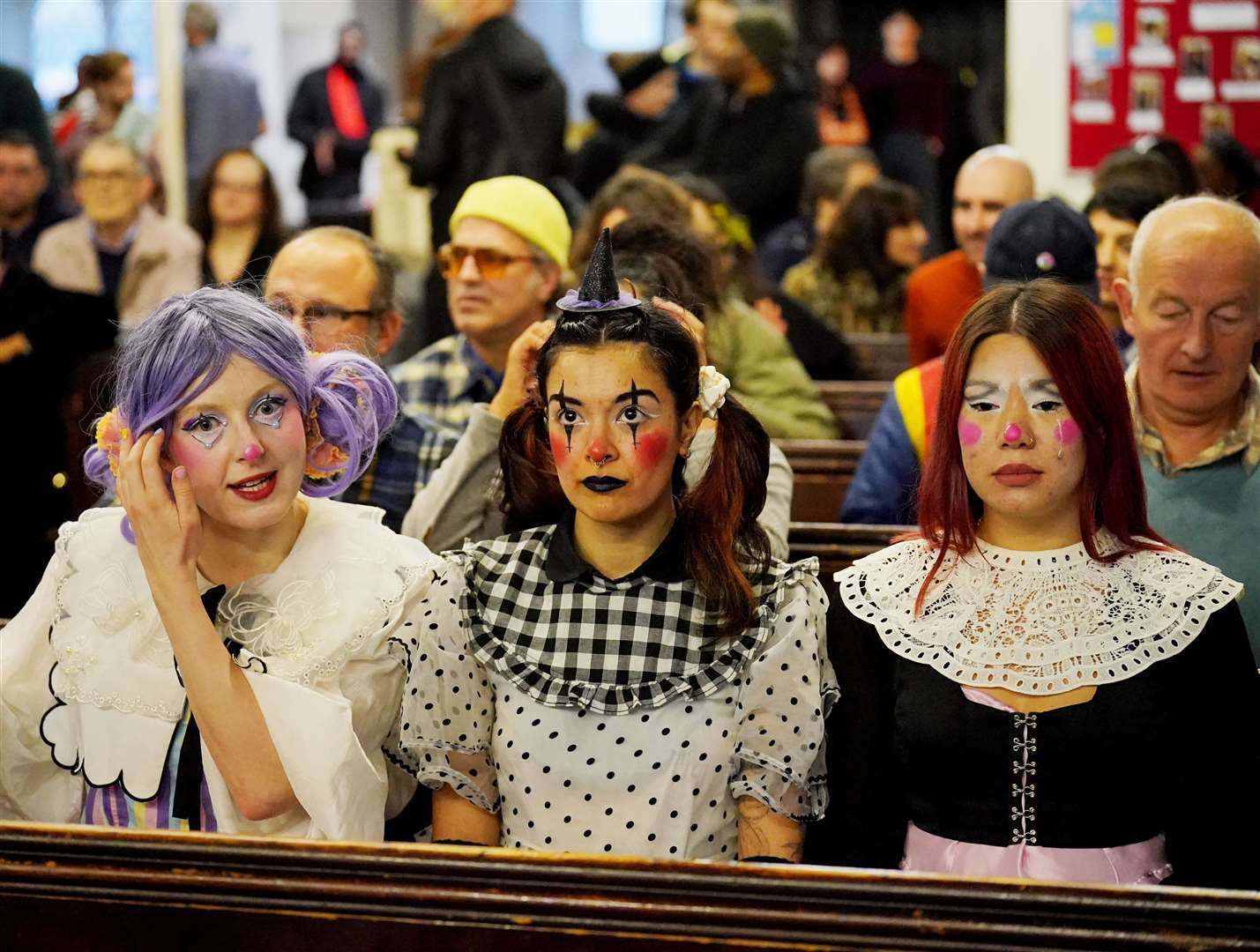 A group wearing elaborate face make-up, with one also sporting a tiny hat on her head (Jonathan Brady/PA)