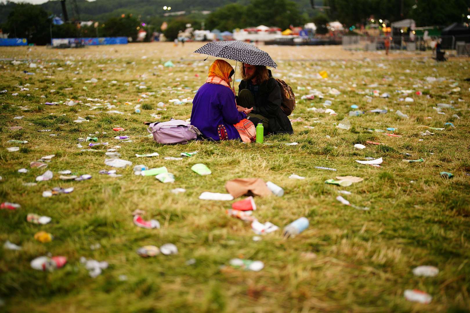 Festival-goers sit amongst the waste (Ben Birchall/PA)