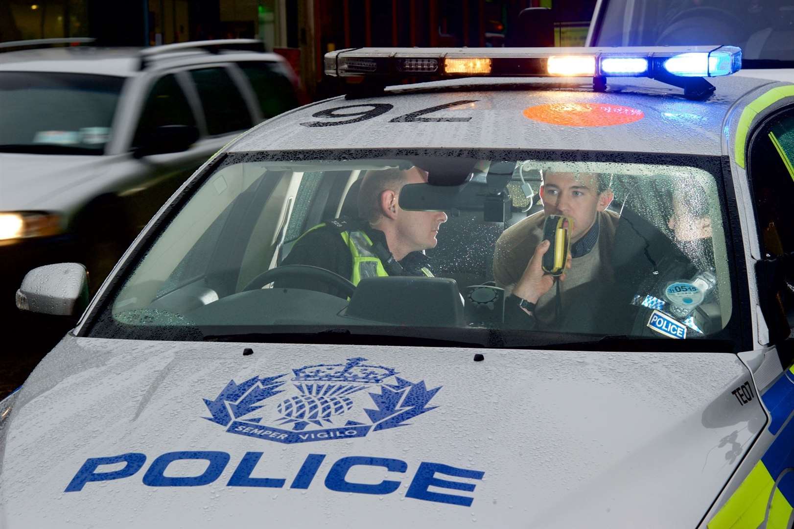 A police officer breathalysing a motorist