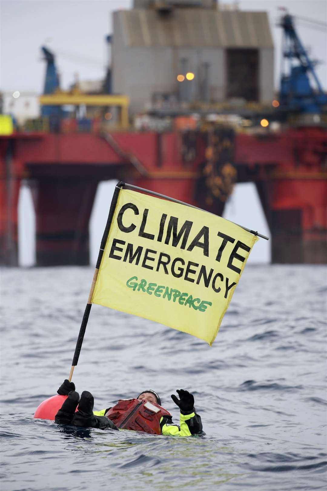 A Greenpeace campaigner holds a banner while floating in front of the rig during the protest. Picture: Greenpeace