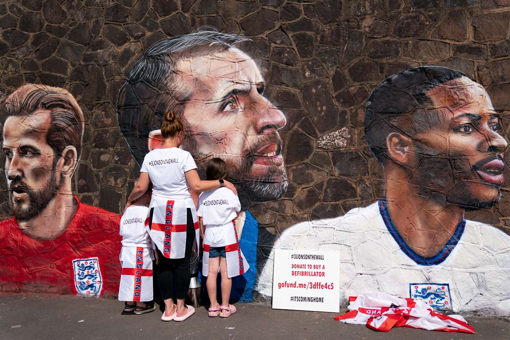 Fans by a new mural in Nuneaton by artist Nathan Parker, depicting Gareth Southgate, Harry Kane and Raheem Sterling (Jacob King/PA)