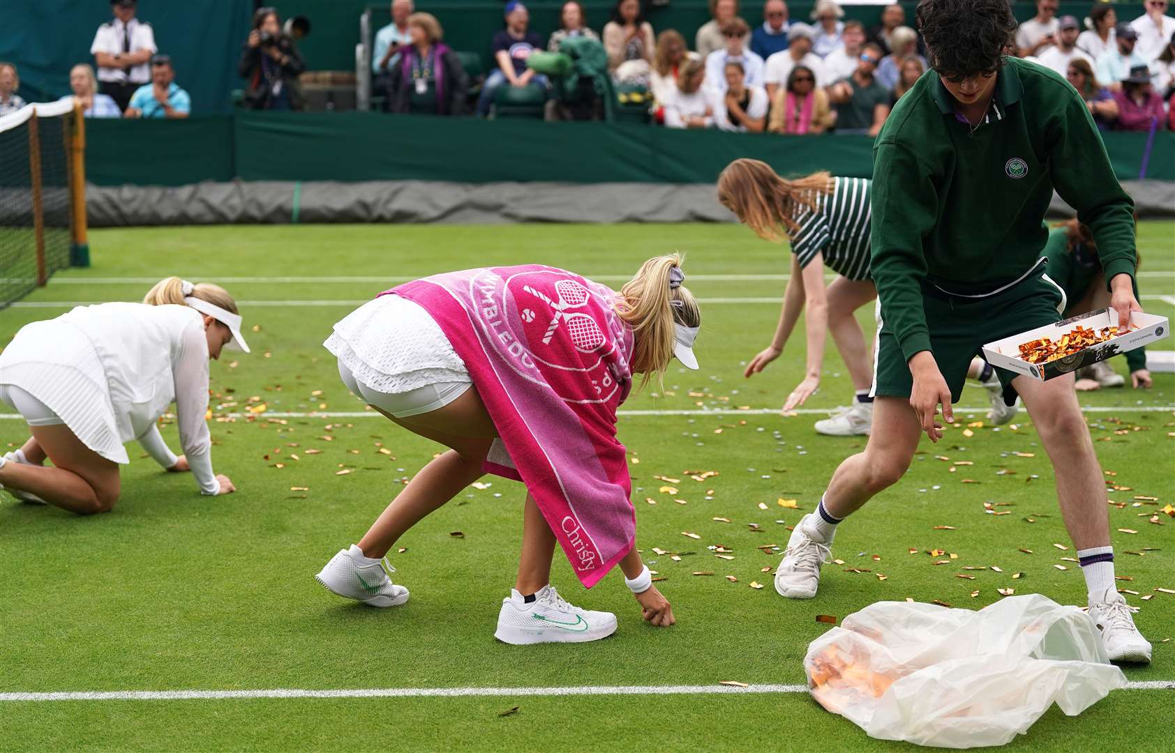 Katie Boulter helps ground staff clear confetti from court 18 (Adam Davy/PA)