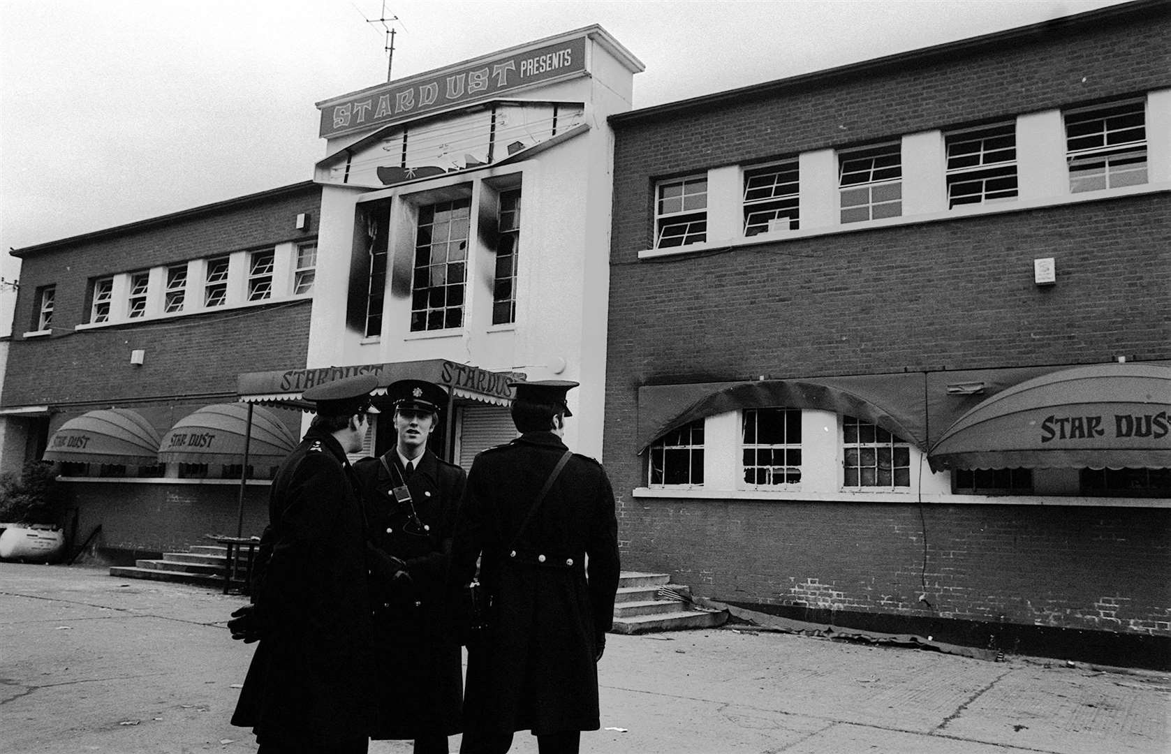 Police stand outside the main entrance of the devastated building in Artane, Dublin, in 1981 (Tony Harris/PA)