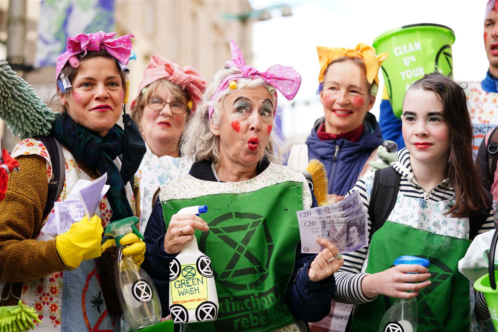 They posed in aprons with cleaning products for the ‘greenwashing’ protest (Jane Barlow/PA)