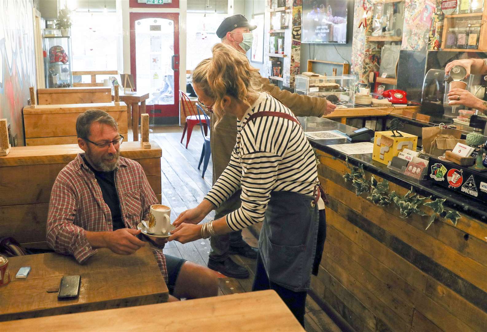 Comicoffee customer Charlie Way (left) receives his coffee from Lucy Jackson in Newport, Isle of Wight (Steve Parsons/PA)